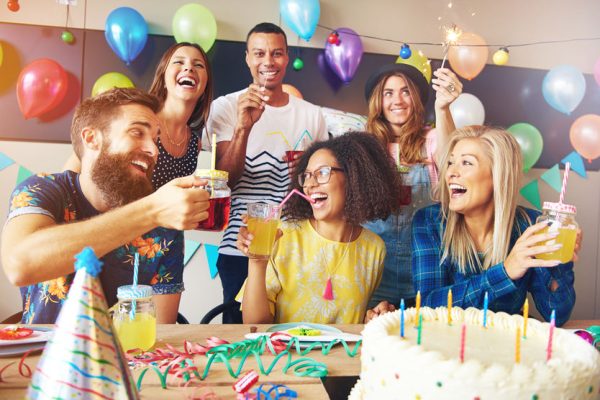 Happy exuberant group of friends celebrating a birthday party toasting the birthday girl laughing and joking